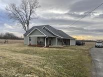 Charming single-story home featuring a covered porch, gray siding, and a well-maintained lawn at 8221 S 300 W, Muncie, IN 47302