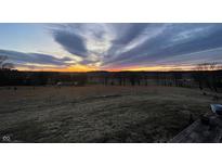 Scenic view of a vibrant sunset over a grassy field with trees in the distance at 1125 S Buffalo Hill Rd, Martinsville, IN 46151