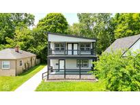 Charming two-story home featuring a spacious double-decker porch with stylish black railings and a well-maintained lawn at 4242 Winthrop Ave, Indianapolis, IN 46205