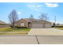 Beautiful single-story brick home featuring an attached three car garage and well-manicured lawn at 4929 Imperial Dr, Columbus, IN 47203