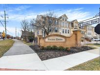 Welcoming 'Village Green' brick sign in a well-maintained community on W Smoky Row under a partly cloudy, blue sky at 700 Greenford N Trl, Carmel, IN 46032