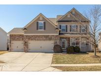 Charming two-story home with brick and siding, an attached three-car garage, and a cozy front porch at 7728 Solomon Dr, Zionsville, IN 46077