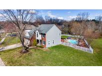 Aerial view of charming two-story home with a well-manicured lawn and in-ground pool surrounded by a white picket fence at 8452 Sunningdale Blvd, Indianapolis, IN 46234
