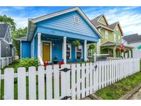 Charming blue home featuring a white picket fence, cozy front porch, and well-maintained landscaping at 912 Harlan St, Indianapolis, IN 46203