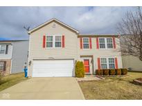 Charming two-story home featuring a two car garage, landscaped yard, and vibrant red shutters and front door at 10708 Inspiration Dr, Indianapolis, IN 46259