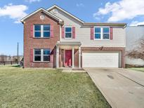 Inviting two-story home featuring a brick facade, vinyl siding, attached garage and a well-manicured lawn at 10830 Clear Spring Dr, Camby, IN 46113
