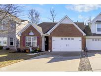 Charming single-story brick home featuring a two-car garage, a well-manicured lawn, and lovely landscaping at 1307 Estuary Dr, Indianapolis, IN 46217