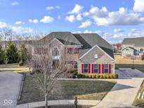 Traditional two-story home featuring brick facade, red shutters, mature trees, and a well-manicured lawn at 4520 Waterchase Ct, Zionsville, IN 46077