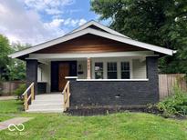 Charming single-story home featuring dark brick accents, a cozy front porch, and a well-manicured lawn at 744 Wallace Ave, Indianapolis, IN 46201