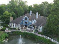 Stunning aerial view of a blue house with lush landscaping and a serene water feature at 8061 Lower Bay Ln # 1, Indianapolis, IN 46236