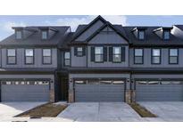 Gray townhome exterior featuring a three-car garage, dark trim, and modern design at 9730 Behner Dr, Fishers, IN 46250