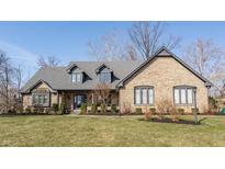 Charming brick home featuring dormer windows, a covered porch, manicured landscaping, and a well-maintained lawn at 13852 Silver Stream Dr, Carmel, IN 46032