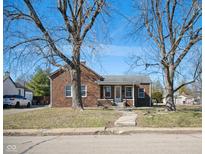 Charming brick home with a covered front porch, mature trees, and a well-maintained lawn at 2022 Newton St, Columbus, IN 47201