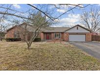 Charming brick home featuring an attached two car garage and a welcoming red front door at 252 N Raceway Rd, Indianapolis, IN 46234