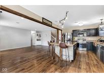 A modern kitchen with an island, wooden beam, and bar seating in an open-concept layout at 659 Melrose Ct, Greenfield, IN 46140