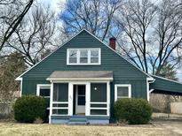 Charming green home with a screened porch and mature trees in a residential neighborhood at 7047 Evanston Ave, Indianapolis, IN 46220