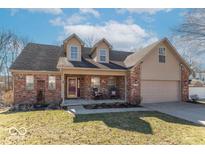 Charming brick home featuring a cozy front porch, dormer windows, and a well-maintained lawn at 7331 Autumn Ct, Avon, IN 46123