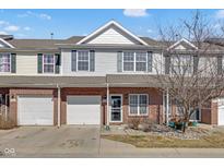 Charming two-story townhouse features a brick facade and a one-car garage, nestled under a partly cloudy sky at 9730 Prairie Smoke Dr, Noblesville, IN 46060