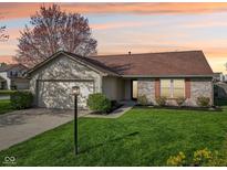 Charming single-Gathering home featuring a manicured lawn, attached garage, and brick accents under a colorful sunset at 2020 Cross Willow Ln, Indianapolis, IN 46239