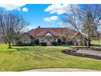 Expansive brick home with manicured lawn and mature trees on a sunny day at 2605 Durbin Ct, Carmel, IN 46032