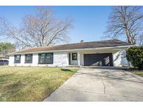 Charming one-story home with a white brick exterior, black shutters, and attached garage on a large lot at 3436 W 61St St, Indianapolis, IN 46228