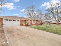 Charming brick ranch home features a two car garage, mature trees, and well maintained lawn at 504 Pelenor Dr, Franklin, IN 46131