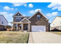 Charming two-story brick home with a two-car garage and inviting front porch in a suburban neighborhood at 7800 Walker Cup Dr, Brownsburg, IN 46112
