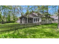 Charming home with a screened porch and a white picket fence surrounded by mature trees and a green lawn at 8190 Jordan Ln, Indianapolis, IN 46240
