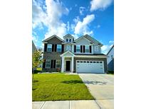 Charming two-story home with a well-manicured lawn, gray brick and gray siding, a 2-car garage, and black shutters at 10202 Meadow Path Ln, Indianapolis, IN 46239