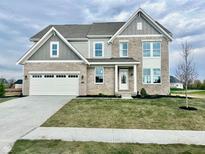 Charming two-story home featuring a gray brick facade, attached two-car garage and a well-manicured lawn at 1101 Knoll Ct, Greenwood, IN 46143