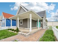 Inviting home featuring a covered front porch, gray siding, crisp white trim, and an eye-catching turquoise front door at 1804 Spann Ave, Indianapolis, IN 46203