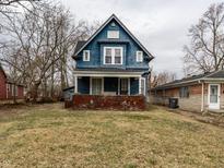 Charming two-story blue home featuring a covered front porch with brick base and classic architectural details at 44 S Bolton Ave, Indianapolis, IN 46219