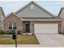 Charming brick home featuring a two-car garage, cozy front porch, and manicured lawn at 5784 Cherrywood Ln, McCordsville, IN 46055