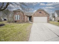 Charming brick home featuring an attached two-car garage and well-maintained lawn at 7031 Sea Eagle Ct, Indianapolis, IN 46254