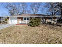 Charming single-story home features a brick facade, white trim, and an attached one car garage at 8230 E 12Th St, Indianapolis, IN 46219
