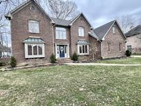 Charming brick home featuring manicured lawn, blue front door with wreath, and mature landscaping at 895 Baywood Ct, Columbus, IN 47201