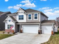 Charming two-story home with a three car garage, landscaped yard, and an American flag at 9264 Larson Dr, Pendleton, IN 46064