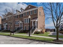 Charming brick townhouse with well-maintained landscaping, a welcoming entrance, and a community street view at 12723 Apsley Ln, Carmel, IN 46032