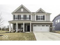 Charming two-story home featuring a brick facade, attached two-car garage and covered porch with seating area at 4078 Omaha Dr, Bargersville, IN 46106