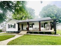 Charming home featuring a covered front porch with stylish seating and beautifully landscaped front yard at 504 S Main St, Waldron, IN 46182