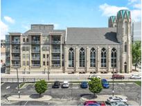An exterior view of a modern apartment building attached to a historic church with ample parking at 802 N Meridian St # 205, Indianapolis, IN 46204