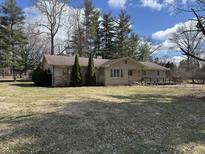 Ranch style home with stone facade, small porch, and trees surrounding the property at 1725 E 110Th St, Carmel, IN 46280