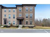 Beautiful three-story brick townhome with a welcoming entrance and well-maintained landscaping at 348 Brunswick Way, Zionsville, IN 46077