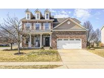 Charming two-story brick home featuring a front porch, well-manicured lawn and attached two car garage at 5524 Goodwin St, Indianapolis, IN 46234