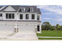 Modern townhome featuring a white facade, black trim, a two-car garage and well-manicured lawn at 10959 Morab Dr, Zionsville, IN 46077