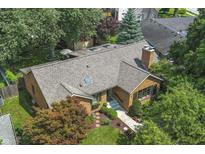 Aerial view of a brick home with a chimney, mature trees, and a well-manicured front yard at 14 Kessler Blvd W Dr, Indianapolis, IN 46208