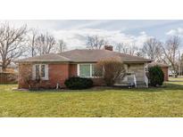 Charming brick ranch home featuring a cozy design, a well-maintained lawn, and neutral color palette at 1559 W 64Th St, Indianapolis, IN 46260
