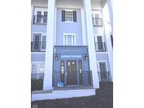 Classic building entrance featuring stately white pillars and dark door with address above, 