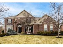 Charming two-story brick home featuring manicured landscaping and an inviting arched entryway at 3880 Heathfield Ct, Zionsville, IN 46077