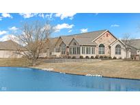 Charming exterior view of a stone and siding home with a beautiful pond in the front yard at 7914 King Post Dr, Indianapolis, IN 46237